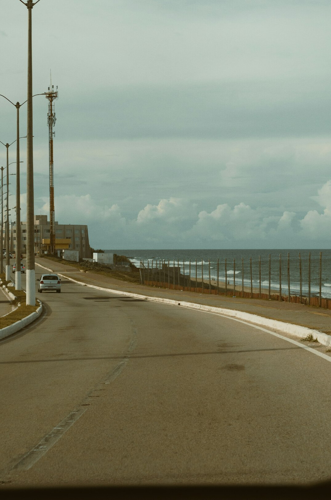 Vintage sports car driving along a coastal road in Punta del Este at sunset